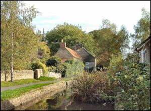 a house next to a river with houses and trees at The Retreat-luxury cottage with hot tub (sleeps 4) 