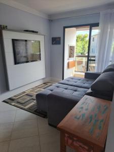 uma sala de estar com um sofá e uma televisão em Residence Portal do Santinho em Florianópolis