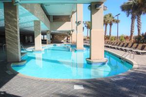 a swimming pool at a hotel with chairs and palm trees at Bahama Sands 1204 in Myrtle Beach