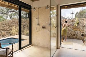 Una mujer parada en una ducha en un baño en Monwana, en Thornybush Game Reserve