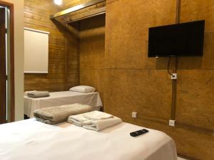 a room with two beds and a flat screen tv at Pousada Canastra Sul in Delfinópolis