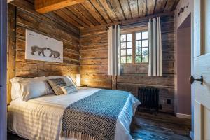 ein Schlafzimmer mit einem Bett in einem Zimmer mit Holzwänden in der Unterkunft CHALET NAHÉLÉ in Val-des-Lacs