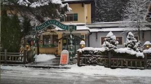 un cartello nella neve davanti a un edificio di Hotel Voglauerhof ad Abtenau