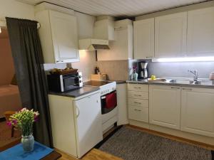 a small kitchen with white cabinets and a microwave at Cozy cottage in quiet location in Oulu