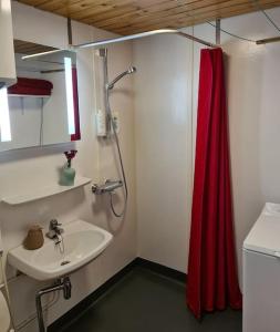 a bathroom with a sink and a red shower curtain at Cozy cottage in quiet location in Oulu