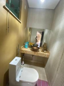 a bathroom with a white toilet and a mirror at Super Casa Piscina Com Cascata in Manaus