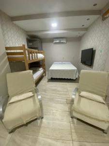 um quarto com uma cama e duas cadeiras e uma televisão em Super Casa Piscina Com Cascata em Manaus