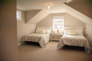 Cette chambre mansardée comprend 2 lits et une fenêtre. dans l'établissement Copper Sky Farm - The Ultimate Country Retreat, 