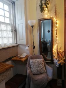 ein Wohnzimmer mit einem Stuhl und einem Spiegel in der Unterkunft Alojamento Local Ferros - Duplex in Viana do Castelo