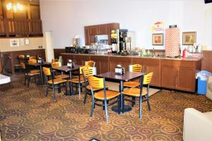 a restaurant with tables and chairs and a kitchen at Super 8 by Wyndham Burlington in Burlington