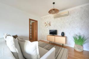 a living room with a white couch and a television at Apartment with Private Terrace & Car Garage in Lisbon