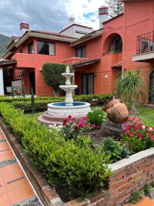 un jardin en face d'une maison avec une fontaine dans l'établissement Hotel Villas Ajijic, Ajijic Chapala Jalisco, à Ajijic