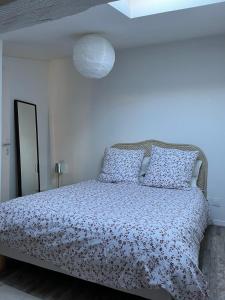 a white bedroom with a bed with a flowery comforter at Le Bourbon in Bordeaux