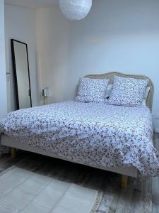 een slaapkamer met een bed met een bloemenbed en kussens bij Le Bourbon in Bordeaux