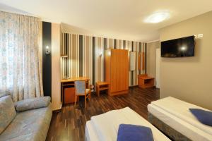 ein Hotelzimmer mit einem Bett, einem Sofa und einem Schreibtisch in der Unterkunft Fair Hotel Villa Diana in Frankfurt am Main