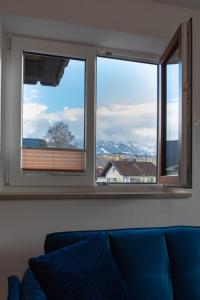 a living room with two windows and a blue couch at AUSZEIT im BERGBLICKparadies - 63 qm Wohlfühloase in Sonthofen