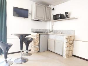 a kitchen with white cabinets and a table and stools at Spa Nimeslodge in Nîmes