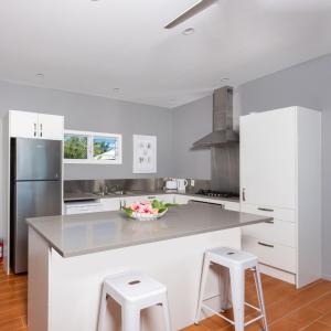 a kitchen with white cabinets and a counter with stools at Panama Beachfront Apartments, Rarotonga in Rarotonga