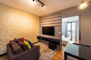 sala de estar con sofá y TV de pantalla plana en SN10 - Apartamento amplo de um quarto, totalmente equipado, próximo à Avenida Paulista., en São Paulo