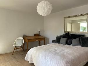 1 dormitorio con cama, escritorio y espejo en Le Hameau du Montchervet, en Puidoux