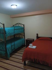 um quarto com 2 beliches e um cobertor vermelho em Hostal Puertas Del Sol em Riobamba