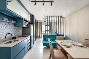 cocina y comedor con armarios azules y mesa en Mi1209 Studio Moderno Prox Paulista e Parque Augusta, en São Paulo