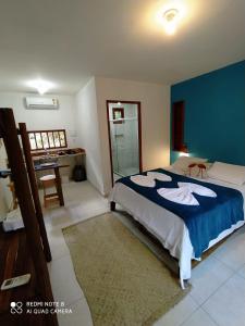 ein Schlafzimmer mit einem großen Bett mit blauer Wand in der Unterkunft Vila Hen Praia do Forte - Studios com Varanda e Piscina - Quintas do Castelo da Torre - Reserva Sapiranga - 3,6km da Vila in Praia do Forte