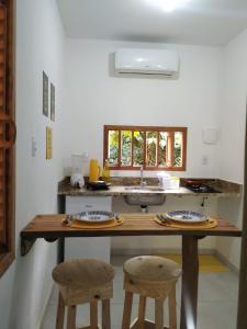 een keuken met een houten tafel en 2 krukken bij Vila Hen Praia do Forte - Studios com Varanda e Piscina - Quintas do Castelo da Torre - Reserva Sapiranga - 3,6km da Vila in Praia do Forte