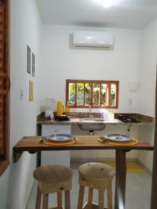 eine Küche mit einem Holztisch und 2 Hockern in der Unterkunft Vila Hen Praia do Forte - Studios com Varanda e Piscina - Quintas do Castelo da Torre - Reserva Sapiranga - 3,6km da Vila in Praia do Forte