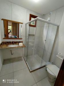 ein Bad mit einer Glasdusche und einem WC in der Unterkunft Vila Hen Praia do Forte - Studios com Varanda e Piscina - Quintas do Castelo da Torre - Reserva Sapiranga - 3,6km da Vila in Praia do Forte
