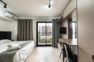 1 dormitorio con cama, escritorio y balcón en IA5 - Studio Incrível e Moderno em Moema, Totalmente Equipado., en São Paulo
