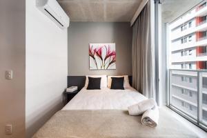 1 dormitorio con cama y ventana grande en VNF917 Studio aconchegante perto do Shopping, en São Paulo