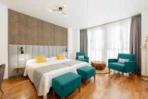 1 dormitorio con 1 cama y 2 sillas azules en Apartamentos Debambú, en Málaga