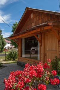 a small house with red flowers in front of it at Cabaña Le Betulle in San Martín de los Andes