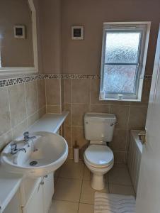 a bathroom with a toilet and a sink and a window at 3 bedroom detached by the sea in Prestatyn