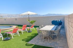 een patio met een tafel en stoelen en een parasol bij Sentiero Haven Permit# 50114 in Indio