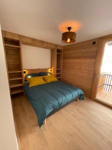 Un dormitorio con una cama con paredes de madera y una ventana en les Airelles 202 en Les Carroz d'Araches