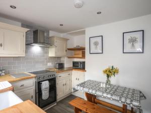 a kitchen with a stove and a table in it at Gwynle - Llanystumdwy in Llanystumdwy