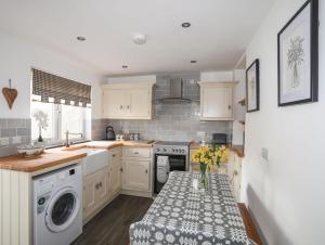 a kitchen with white cabinets and a vase of flowers on a table at Gwynle - Llanystumdwy in Llanystumdwy +17 photos