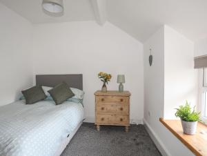 a bedroom with a bed and a wooden nightstand at Gwynle - Llanystumdwy in Llanystumdwy