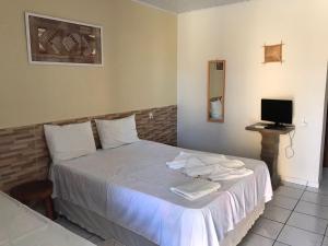 a bedroom with a bed with white sheets and a television at Torre do Sol in Praia do Frances