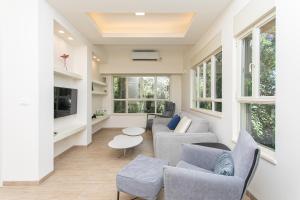 un soggiorno con divano, sedie e TV di Carmel Boutique Apartments - Urban Forest a Haifa