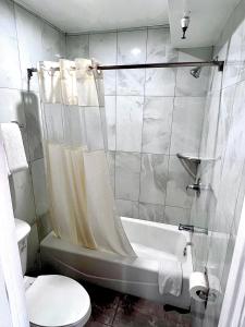 La salle de bains est pourvue d'une baignoire, de toilettes et d'un lavabo. dans l'établissement Paradise Inn, à Montebello