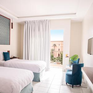 a hotel room with two beds and a blue chair at Hotel Safia in Marrakech