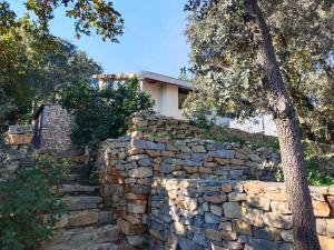 una pared de piedra con un árbol delante de una casa en Spa Nimeslodge, en Nimes