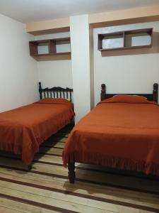 two beds sitting next to each other in a room at Hostal Puertas Del Sol in Riobamba