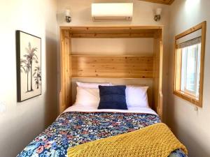 um pequeno quarto com uma cama e uma cabeceira em madeira em Sunshine Tiny Home Near Downtown SLO em San Luis Obispo