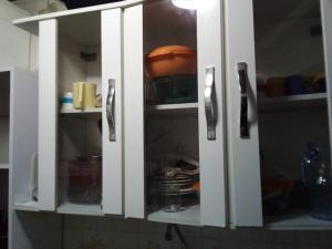 a white cabinet with doors open in a kitchen at Kitinete em Itanhaem in Itanhaém