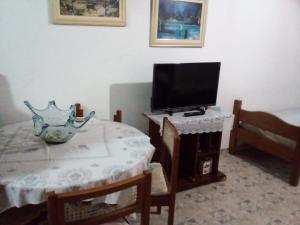 a living room with a table and a television at Kitinete em Itanhaem in Itanhaém