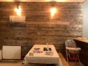 a table and chairs in a room with a wooden wall at Le cocon des écureuils in Font-Romeu-Odeillo-Via